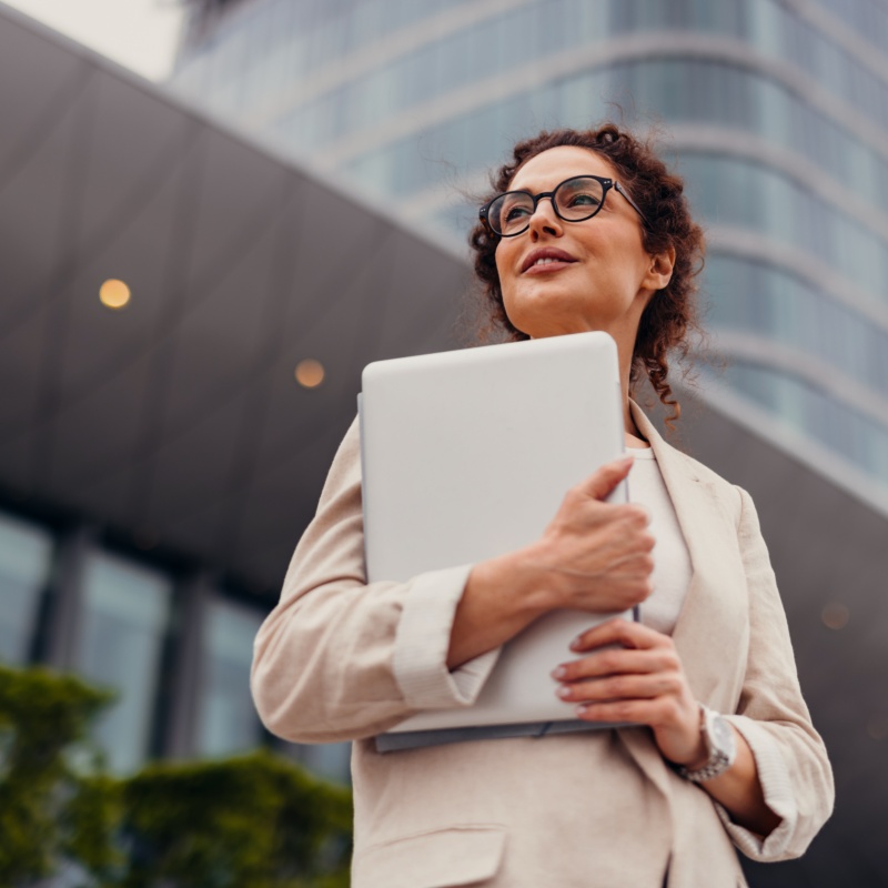 Businesswoman holding laptop looking into distance