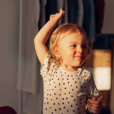Child giving a high five to an adult in a home, with another adult watching and smiling.