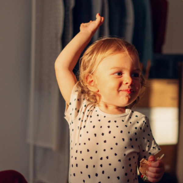 Child giving a high five to an adult in a home, with another adult watching and smiling.