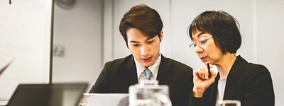 A CFO and CHRO collaborating at an office desk with a laptop.
