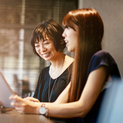 Two people sitting at an office desk with a laptop and financial report