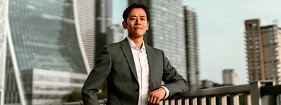 Man standing on bridge in front of city skyline.