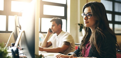 Employee working at a desk in an open concept office. 