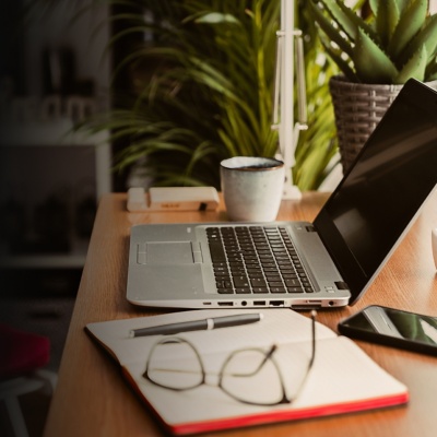 Desk with computer, notebook, and glasses strewn about