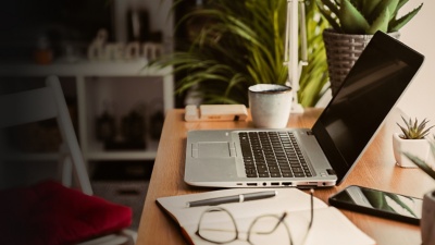 Desk with computer, notebook, and glasses strewn about