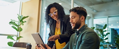 Two colleagues working on a laptop together in an office. 