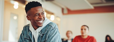 Male student sitting in a class smiling