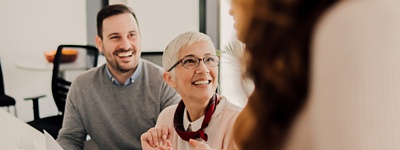Man and woman in glasses smiling at coworker