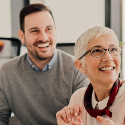 Man and woman in glasses smiling at coworker