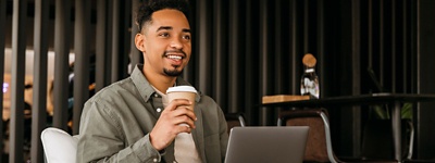 Man holding cup on computer smiling