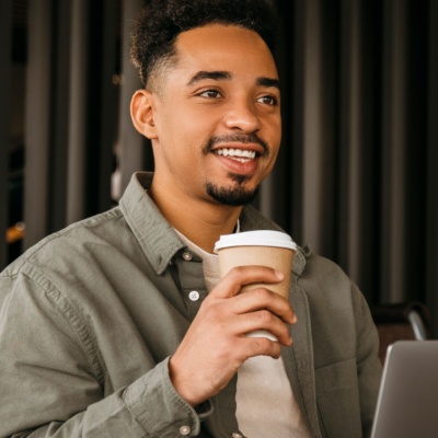 Man holding cup on computer smiling