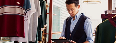 Man in clothing store typing on tablet