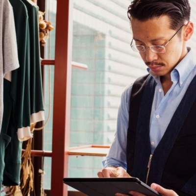 Man in clothing store typing on tablet