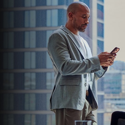 Man looking at analytics on phone in front of conference room window.