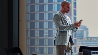 Man looking at analytics on phone in front of conference room window.