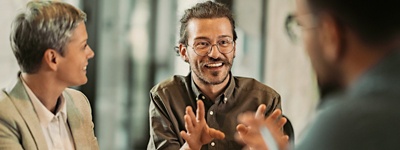 Man with glasses smiling and talking in conversation
