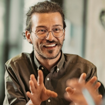 Man with glasses smiling and talking in conversation