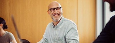 Man with glasses smiling looking at coworker to the side