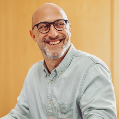 Man with glasses smiling looking at coworker to the side