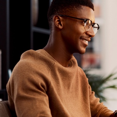 Hombre con gafas sonriente en un escritorio mirando un monitor