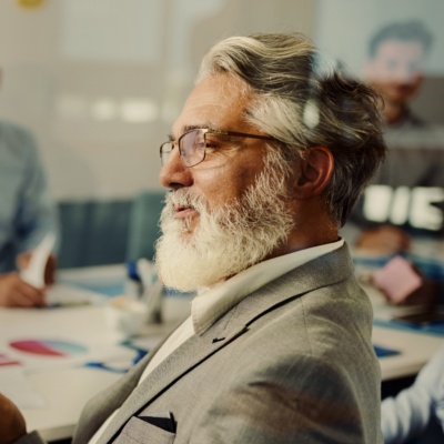 Man with glasses talking to woman at table with colleagues