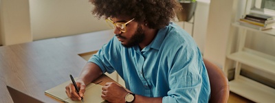Man smiling at laptop with woman at laptop and other coworkers