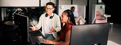 man with headphones and woman looking at computer