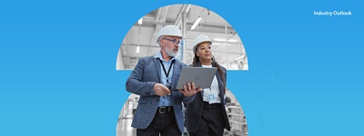 Two manufacturing employees wearing hard hats in a warehouse