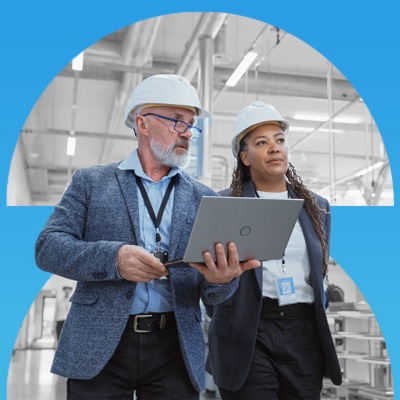 Two manufacturing employees wearing hard hats in a warehouse