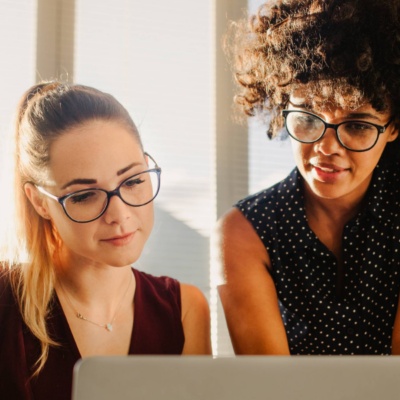 Two colleagues collaborating over a laptop in a bright office