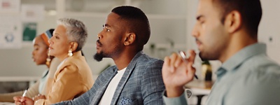 People sitting at table looking ahead one person in focus