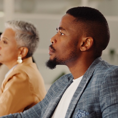 People sitting at table looking ahead one person in focus
