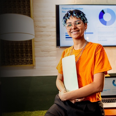 A person holding files in front of a screen showing financial plans.