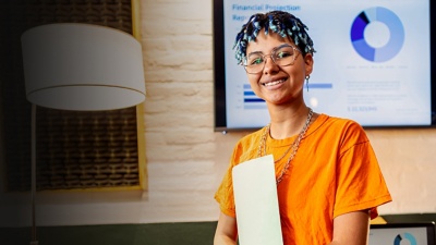 A person holding files in front of a screen showing financial plans.