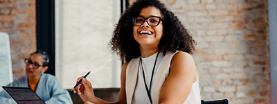 Person smiling with glasses holding pen