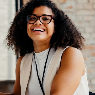 Person smiling with glasses holding pen
