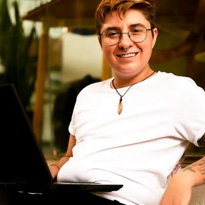 Person with glasses smiling and sitting with laptop on lap