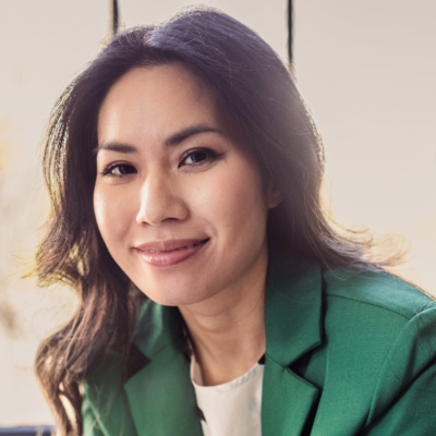 An SMB leader sitting on a couch with her phone, smiling at the camera.
