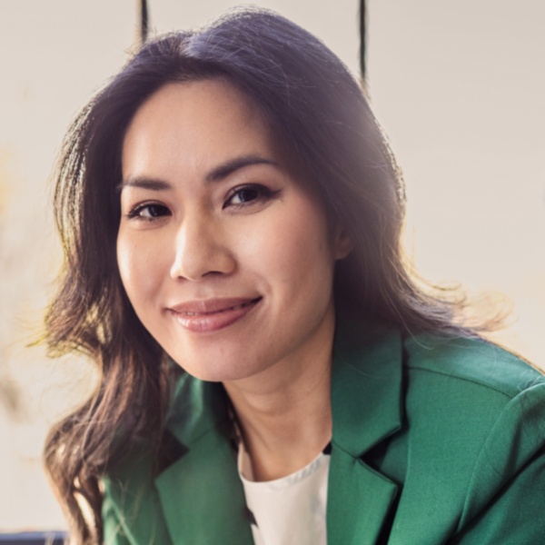 An SMB leader sitting on a couch with her phone, smiling at the camera.