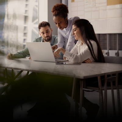 Three people in an office looking at a laptop