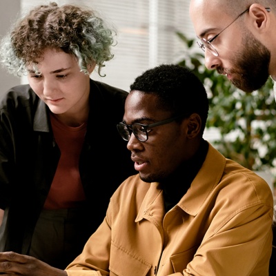 three people looking at laptop