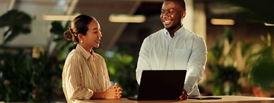 Two coworkers standing smiling up at desk