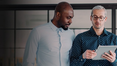 Two men looking at a table in an office while talking