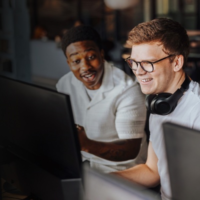 Two colleagues smiling and looking at a computer screen