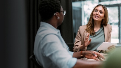 Person holding a tablet talking to colleagues at a conference table
