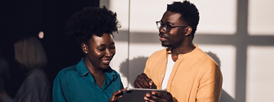 Two people smiling down looking at tablet