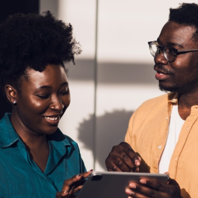 Two people smiling down looking at tablet