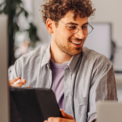 Two people with glasses smiling looking at tablet