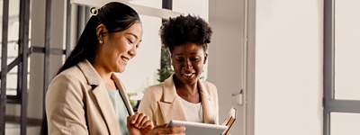 Two women smiling and looking at a tablet