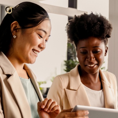 Two women smiling and looking at a tablet